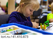 Child girl 5 year old inventing robot in programming classroom, construct robotic toys. Kid using constructor blocks and PC, technology homework. Learning robotics basics concept. Copy ad text space. Стоковое фото, фотограф Aleksandr Golubev / Фотобанк Лори