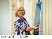 Mature blonde woman with credit card in hand near ATM. Стоковое фото, фотограф Андрей Аркуша / Фотобанк Лори