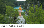 Woman tourist enjoying mountain view over lake with turquoise water and high waterfalls. Plitvice La. Стоковое фото, фотограф Igor Tichonow / Фотобанк Лори