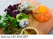 Salmon tartar with balsamic, greens, lemon, quail egg on wooden desk. Стоковое фото, фотограф Яков Филимонов / Фотобанк Лори