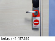 In the hallway of the hotel there is a sign do not disturb  on the door handle of the hotel room. В коридоре отеля на дверной ручке гостиничного номера висит табличка "Не беспокоить" Стоковое фото, фотограф Дмитрий Березнев / Фотобанк Лори