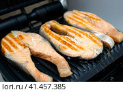 Three salmon steaks are grilled on a modern electric grill with a non-stick coating. The concept of healthy eating. Три стейка из лосося готовятся на современном электрическом гриле с антипригарным покрытием. Концепция здорового питания. Стоковое фото, фотограф Дмитрий Березнев / Фотобанк Лори