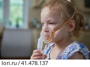 Sick little girl making inhalation with nebulizer to reduce coughing at home, child taking medication while breathing in through face mask. Bronchitis and asthma treatments for children. Стоковое фото, фотограф Кутина Татьяна / Фотобанк Лори