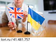 Unrecognizable girl sets midget Ukrainian and Britannic flags before international negotiations. Стоковое фото, фотограф Яков Филимонов / Фотобанк Лори
