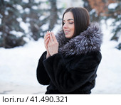 Young woman warms her palms with her breath in the frosty weather of her palms. Стоковое фото, фотограф Андрей Аркуша / Фотобанк Лори