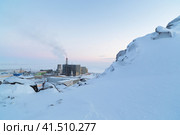 Зимний промышленный пейзаж с заснеженным горным склоном и теплоэлектростанцией. Энергетика и экология Арктики. Электростанция на Крайнем Севере России. Анадырь, Чукотка, Сибирь. Холодная погода. Стоковое фото, фотограф Андрей Степанов / Фотобанк Лори