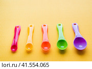 Мерные ложки на желтом фоне. Разноцветные пластиковые мерные ложки. Measuring spoons on a yellow background. Multi-colored plastic measuring spoons. Стоковое фото, фотограф Ольга Митряева / Фотобанк Лори