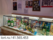Бутылки водки, спирта, одеколона и другие экспонаты в витрине. «Музей русской водки» («Музей Русского национального напитка»). Санкт-Петербург (2023 год). Редакционное фото, фотограф Румянцева Наталия / Фотобанк Лори