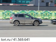 Haval H6 SUV in motion. Gray dirty crossover is fast driving on city street. Side view of car rushing on urban road. Редакционное фото, фотограф Константин Григорьев / Фотобанк Лори