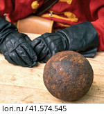 A gunner in vintage Swedish military clothing and cannon balls. Ancient military arsenal of the events of the Russian-Swedish war. Стоковое фото, фотограф Андрей Журавлев / Фотобанк Лори