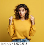 A young, pensive, insecure, rather attractive European girl of 20 years in a yellow casual blouse, spreads her hands questioningly, looking away. Created by AI. Стоковое AI-изображение, AI-художник Ярославский Максим / Фотобанк Лори