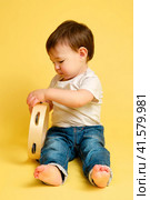 Toddler baby plays the tambourine, a child with a percussion musical instrument on a studio yellow background. Happy child musician playing hand drum. Kid aged one year four months. Стоковое фото, фотограф Андрей Журавлев / Фотобанк Лори