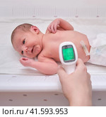 A mother measures the body temperature of a newborn baby with an infrared thermometer. Стоковое фото, фотограф Андрей Журавлев / Фотобанк Лори