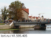 Kaliningrad, Russia - August 22 2022: People on the Honey bridge the summer day. A lot of people. They go for a walk. Pregol River. Touristic lifestyle concept. Fishing village. Редакционное фото, фотограф YuryKara / Фотобанк Лори