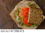 Redfish sandwich with salad and tomatoes laying on a kraft paper. Стоковое фото, фотограф Воловодов Владимир / Фотобанк Лори