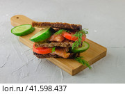 Redfish bread sandwich with cucumber and tomatoes for breakfast laying on a wooden board. Стоковое фото, фотограф Воловодов Владимир / Фотобанк Лори
