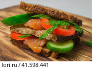 Salmon sandwich with cucumber, herbs and tomatoes laying on a rustic board. Стоковое фото, фотограф Воловодов Владимир / Фотобанк Лори