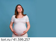 Portrait of a pregnant woman in perplexity on a blue background. Стоковое фото, фотограф Андрей Журавлев / Фотобанк Лори