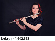 Portrait of a woman musician with a flute on a studio black background. Flutist with a large concert transverse flute in her hands. Стоковое фото, фотограф Андрей Журавлев / Фотобанк Лори