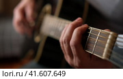 Playing the guitar. Strumming black acoustic guitar. Musician plays music. Man fingers holding mediator. Male hand playing guitar neck in dark room. Unrecognizable person rehearsing, fretboard closeup. Стоковое видео, видеограф Марина Демидюк / Фотобанк Лори