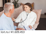 Woman nurse doctor gp holding stethoscope examining old senior 60s grandpa patient check heartbeat at home care checkup medical visit. Стоковое фото, фотограф Гладских Татьяна / Фотобанк Лори