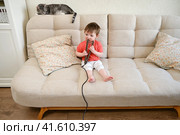 Baby dangerously plays with hair curling tongs, risking burns or injuries. Parents should keep a watchful eye on their little one to prevent accidents. Kid aged about two years (one year ten months). Стоковое фото, фотограф Андрей Журавлев / Фотобанк Лори