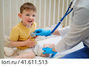 The pediatrician listened to the baby's heartbeat with a stethoscope during the home visit. Kid aged about two years (one year eleven months) Стоковое фото, фотограф Андрей Журавлев / Фотобанк Лори