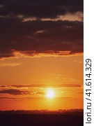 The setting sun created a stunning display of fiery orange and red colors in the evening sky as it disappeared below the horizon. Стоковое фото, фотограф Андрей Журавлев / Фотобанк Лори