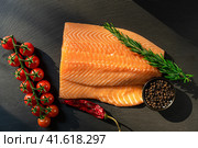 Top view of fresh raw salmon fish steak with spices on a dark stone background. Salt, spices, seasonings and other ingredients. Стоковое фото, фотограф Артем Лукин / Фотобанк Лори