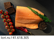 Top view of fresh raw salmon fish steak with spices on a dark stone background. Salt, spices, seasonings and other ingredients. Стоковое фото, фотограф Артем Лукин / Фотобанк Лори