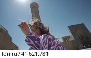 A young woman with long hair in an oriental robe and a skullcap walks through an ancient oriental city. Стоковое видео, видеограф Aleksey Kidisyuk / Фотобанк Лори