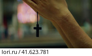 Young guy praying to God in the church. Religious mixed race teenage boy holding a cross in his hand. Стоковое видео, видеограф Igor Tichonow / Фотобанк Лори