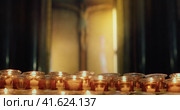Burning candles in the church. Orthodox cross with crucifixion of Jesus Christ. Christian faith in G. Стоковое видео, видеограф Igor Tichonow / Фотобанк Лори