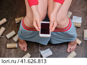 Female legs on the background of the remnants of toilet paper and a phone in her hands. Concept stomach disease, poisoning and diarrhea problems. Стоковое фото, фотограф Андрей Журавлев / Фотобанк Лори