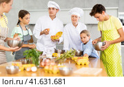 Man and woman cooks, during culinary master class, tell children rules when preparing dough. Стоковое фото, фотограф Яков Филимонов / Фотобанк Лори