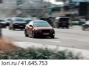 Kia Cerato Koup First generation TD in motion on a city street. Red coupe car Kia Forte Koup moving fast, front side view. Редакционное фото, фотограф Константин Григорьев / Фотобанк Лори