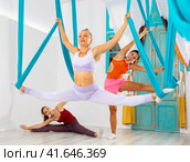 Fit woman doing split on suspended hammocks during antigravity yoga workout. Стоковое фото, фотограф Яков Филимонов / Фотобанк Лори