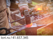 The blacksmith strikes the red blade of the sword with a hammer. Work in the forge to create weapons. The knife is between a rock and a hard place. Стоковое фото, фотограф Андрей Журавлев / Фотобанк Лори