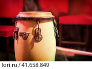 Traditional ethnic Cuban Djembe drum on red background. Percussion instruments made of wood covered with leather. Ethnic drum set at a concert of jazz music. Стоковое фото, фотограф Андрей Журавлев / Фотобанк Лори