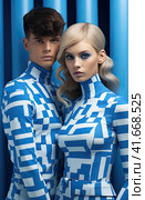 A young smiling cheerful couple, two friends, a family man and a woman in unusual blue designer clothes, stand next to each other, directing their gaze at the camera. Generated by AI. Стоковое AI-изображение, AI-художник Ярославский Максим / Фотобанк Лори