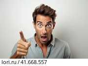 A young handsome man with a beard in a casual sweater on a gray background is afraid and shocked by surprise. Generated by AI. Стоковое AI-изображение, AI-художник Ярославский Максим / Фотобанк Лори