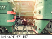 A man clamped in a Vice between two cars. Color photo of a man constrained by circumstances. The guy on the tracks is trapped by machinery. Стоковое фото, фотограф Андрей Журавлев / Фотобанк Лори