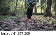 Serious boy with a metal detector examines the soil on a rocky trail on a summer evening. Стоковое видео, видеограф Igor Skripachev / Фотобанк Лори