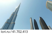 Bottom view of skyscrapers of Dubai city, UAE with Burj Khalifa at blue sky. Panorama urban cityscape of new towers. Construction and architecture concept (2023 год). Редакционное видео, видеограф Aleksandr Golubev / Фотобанк Лори
