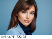 Close-up portrait of beautiful sensual caucasian woman with brown hair wearing blue clothes on a blue background.. AI. Стоковое AI-изображение, AI-художник Sergey Grishin / Фотобанк Лори