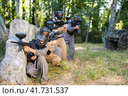 Paintball players of one team in camouflages and masks aiming with gun in shootout. Стоковое фото, фотограф Яков Филимонов / Фотобанк Лори