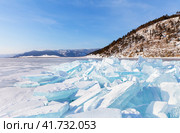 The edge of hummock field with piles of huge transparent blue ice floes near shore of frozen Baikal Lake on frosty sunny day. Beautiful winter landscape. Natural background. Winter travel and outdoors. Стоковое фото, фотограф Виктория Катьянова / Фотобанк Лори