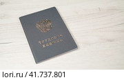 Мужская рука кладет на стол трудовую книжку гражданина Российской Федерации с трудовым стажем. Стоковое видео, видеограф Sergei Gorin / Фотобанк Лори