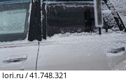 Person brushing fresh snow from car windows after snow storm blizzard. Morning routine difficulties of car owners in cold winter weather. Car window cleaning. Winter season. White snow. Vehicle care. Стоковое видео, видеограф Марина Демидюк / Фотобанк Лори