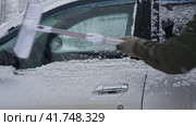 Person brushing fresh snow from car windows after snow storm blizzard. Morning routine difficulties of car owners in cold winter weather. Car window cleaning. Winter season. White snow. Vehicle care. Стоковое видео, видеограф Марина Демидюк / Фотобанк Лори